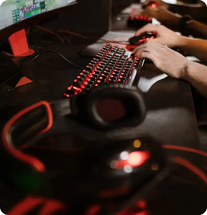 Professional gaming headset hanging on a computer monitor in a modern gaming setup.